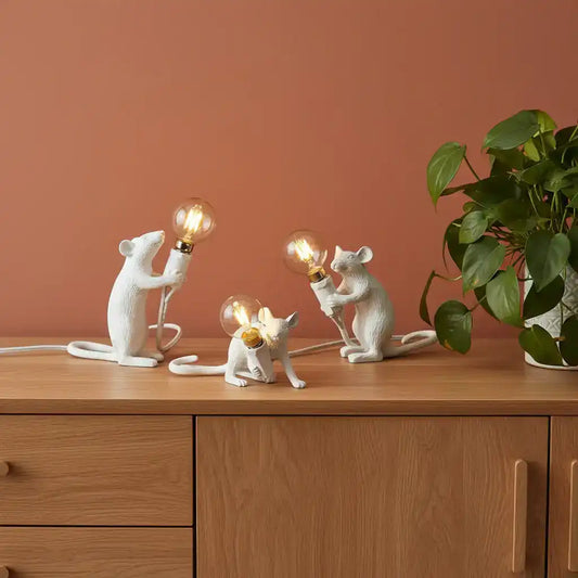 Three white mouse-shaped lamps with light bulbs on a book