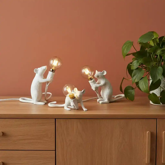 Three white mouse-shaped lamps with light bulbs on a book