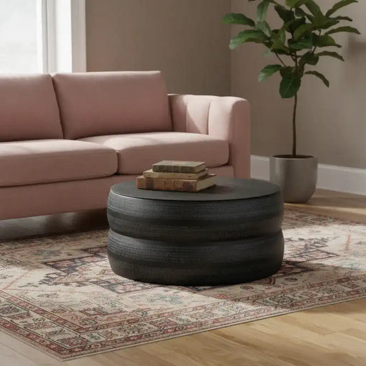 Living room with pink sofa, round black coffee table, and potted plant.
