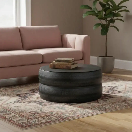 Living room with pink sofa, round black coffee table, and potted plant.