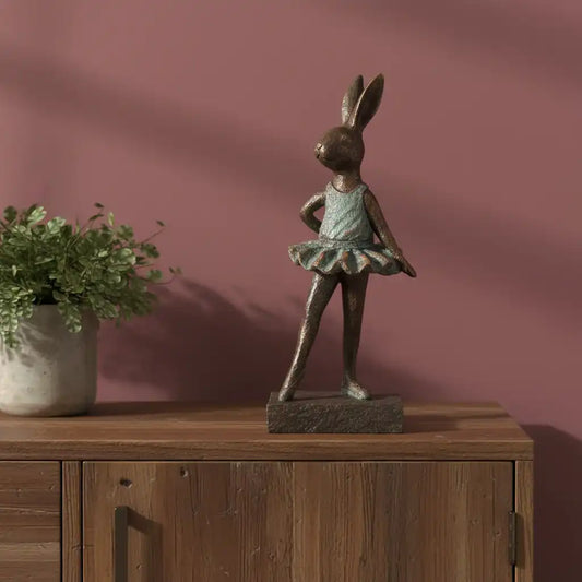 Bronze rabbit sculpture on a wooden surface with a pink wall background