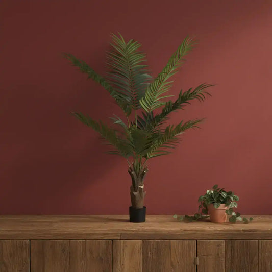 Potted plant on a wooden surface with a red-brown wall background
