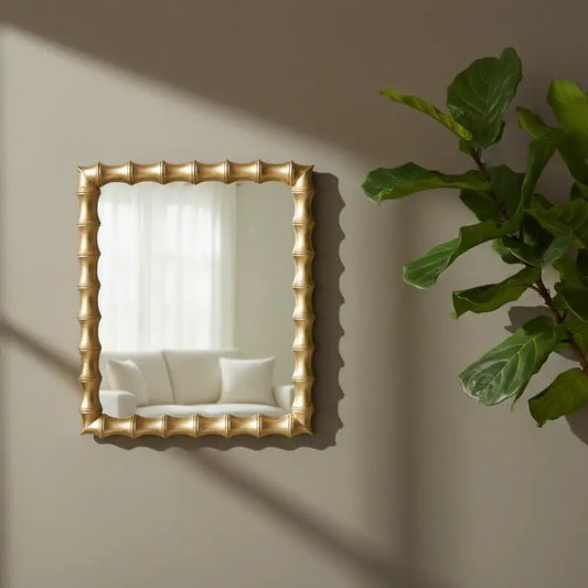 Gold-framed mirror on a wall with a plant to the right
