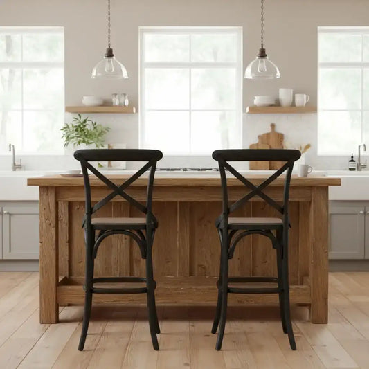 Wooden kitchen island with two black bar stools in a bright kitchen setting.