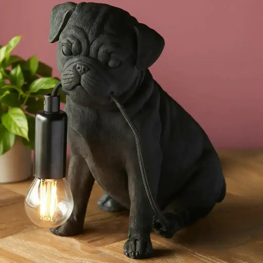 Black dog-shaped lamp with a lit bulb on a wooden surface