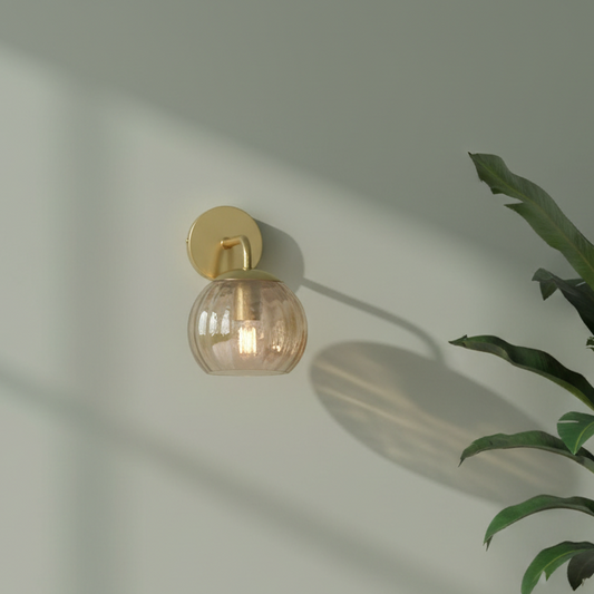 Wall-mounted light fixture with a glass shade on a neutral wall.