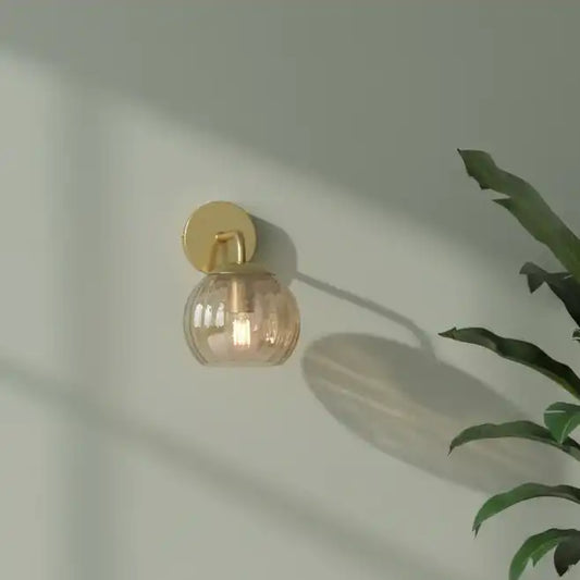 Wall-mounted light fixture with a glass shade on a neutral wall.