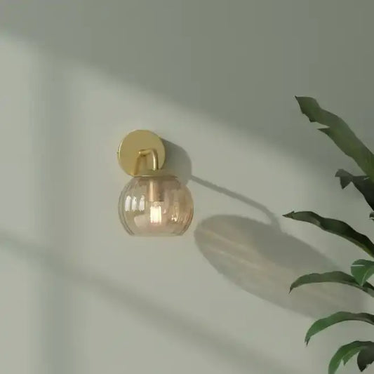 Wall-mounted light fixture with a glass shade on a neutral wall.