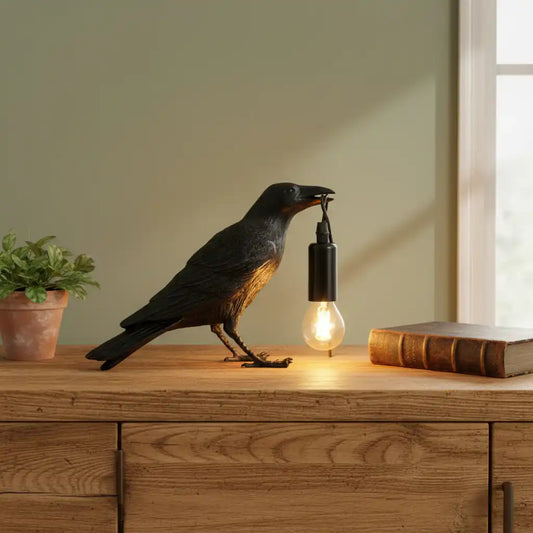 Decorative lamp shaped like a crow with a light bulb in its mouth on a neutral background
