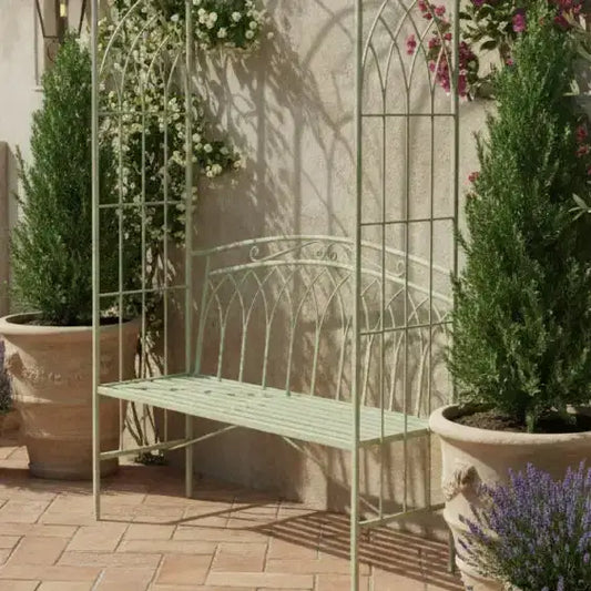 Decorative metal bench with floral arches and potted plants in a garden setting.