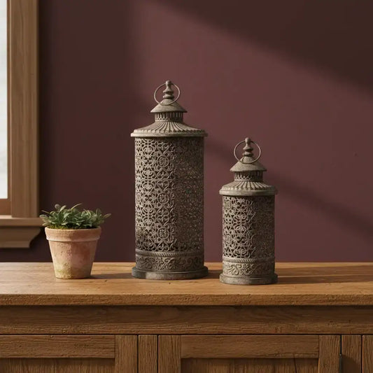 Two ornate lanterns on a wooden surface with a maroon wall in the background