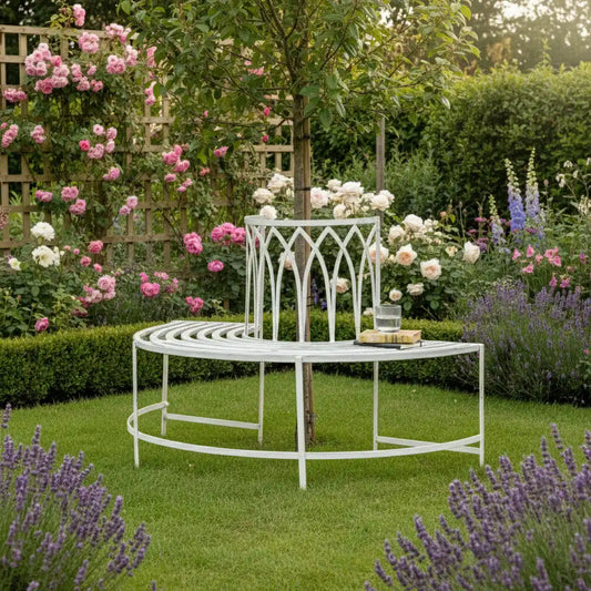 White metal garden bench and table set in a lush garden with flowers and lavender.