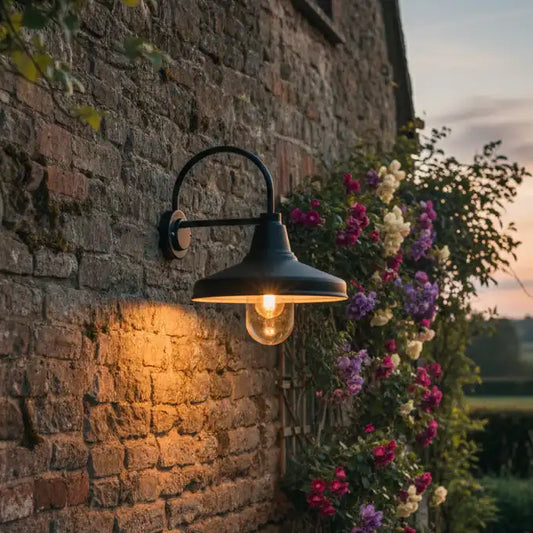 Outdoor wall light fixture on a stone wall with flowers in the background