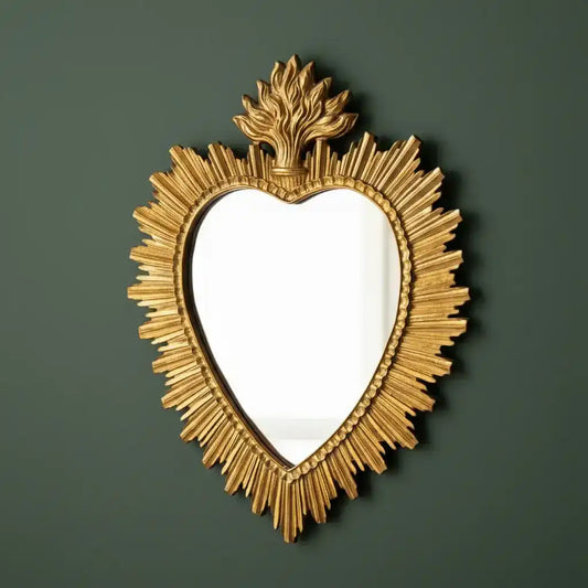 Decorative gold heart-shaped mirror on a dark green background