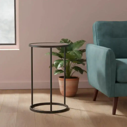 Teal armchair and black metal side table in a room with pink walls and a plant.