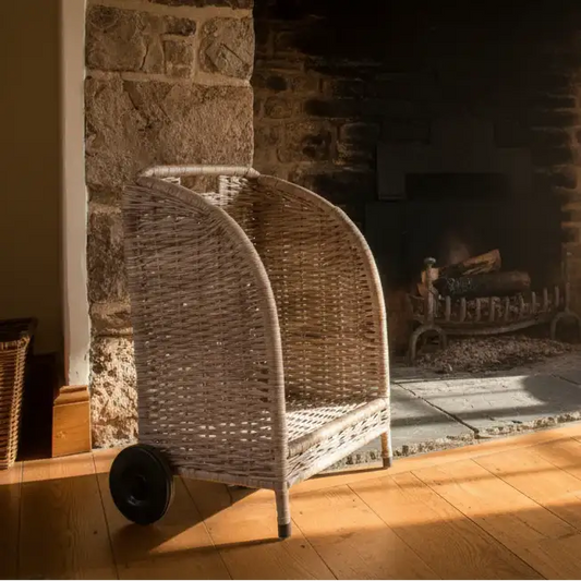Wicker chair in front of a stone fireplace with a fire burning.
