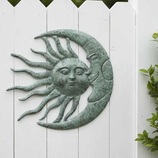 Decorative wall art of a sun and moon with faces on a white wooden background