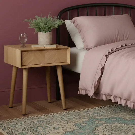 Wooden side table with a drawer, glass of water, and plant on a white background