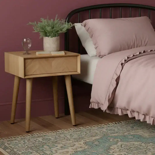 Wooden side table with a drawer, glass of water, and plant on a white background