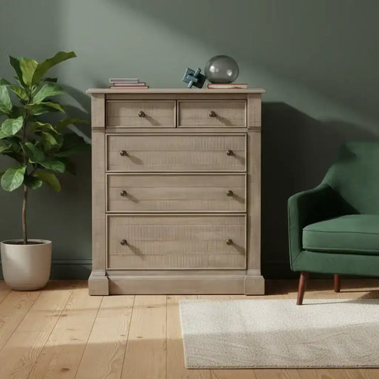 Wooden dresser with decorative items in a room with a green wall, plant, and green sofa.
