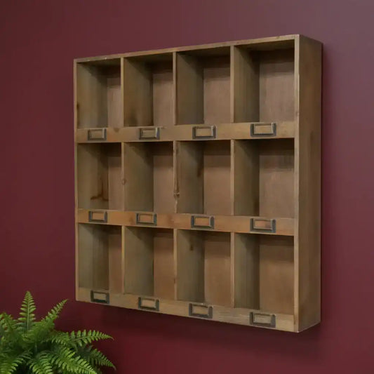 Wooden wall-mounted shelf with multiple compartments against a red wall.