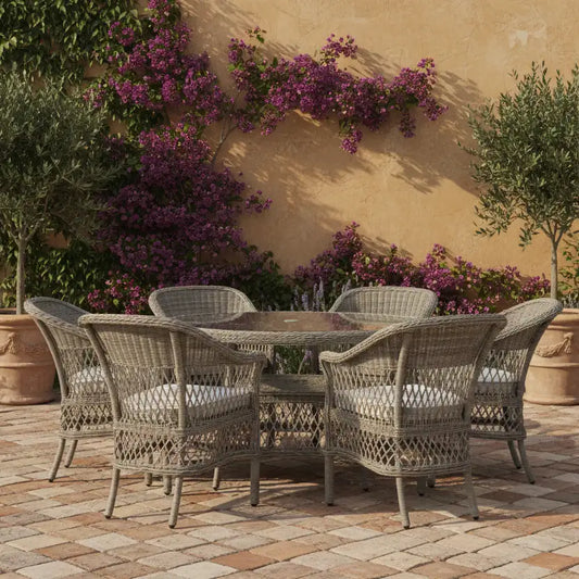Outdoor patio set with wicker chairs and table against a wall with purple flowers.