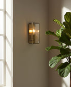 Wall-mounted light fixture with glass enclosure on a white wall