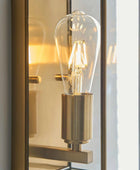 Decorative wall light fixture with a glass bulb inside a reflective mirror.