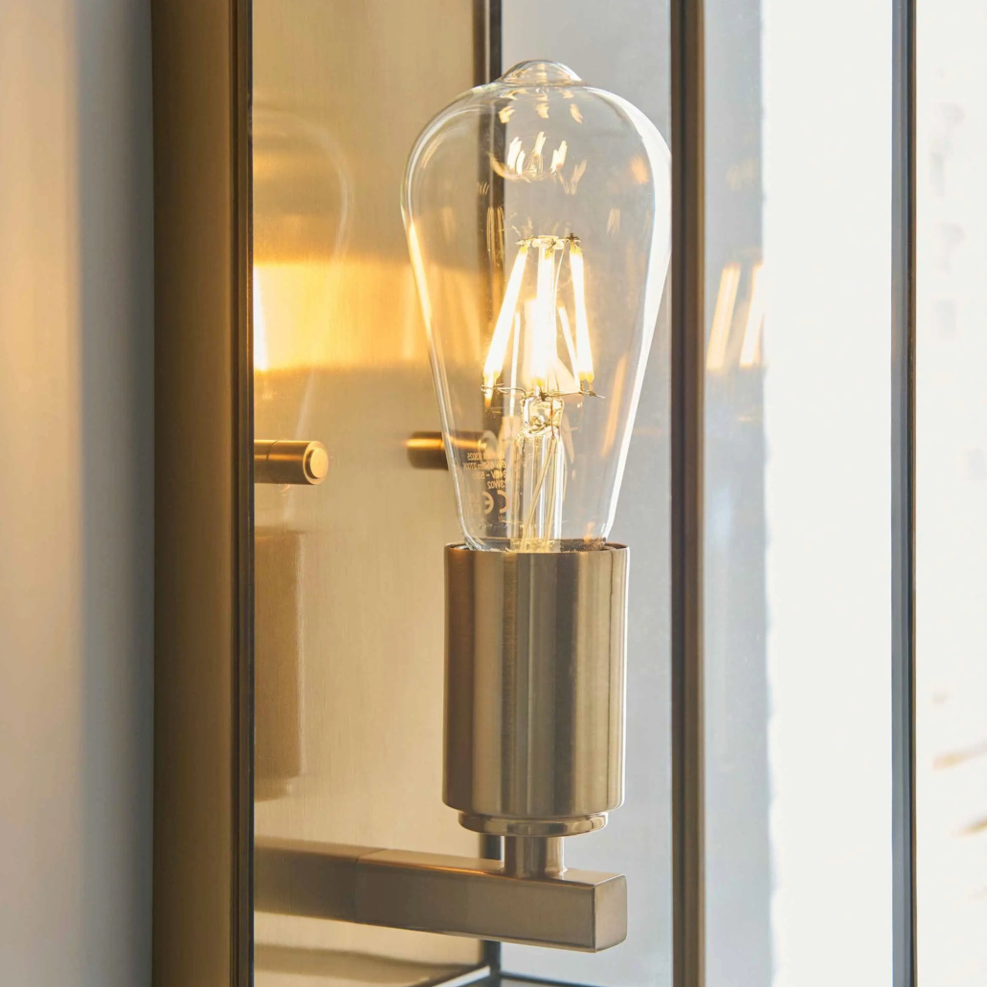 Decorative wall light fixture with a glass bulb inside a reflective mirror.