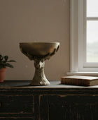 Bronze bowl with deer head design on a wooden surface