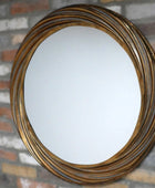Round mirror with a gold frame on a brick wall