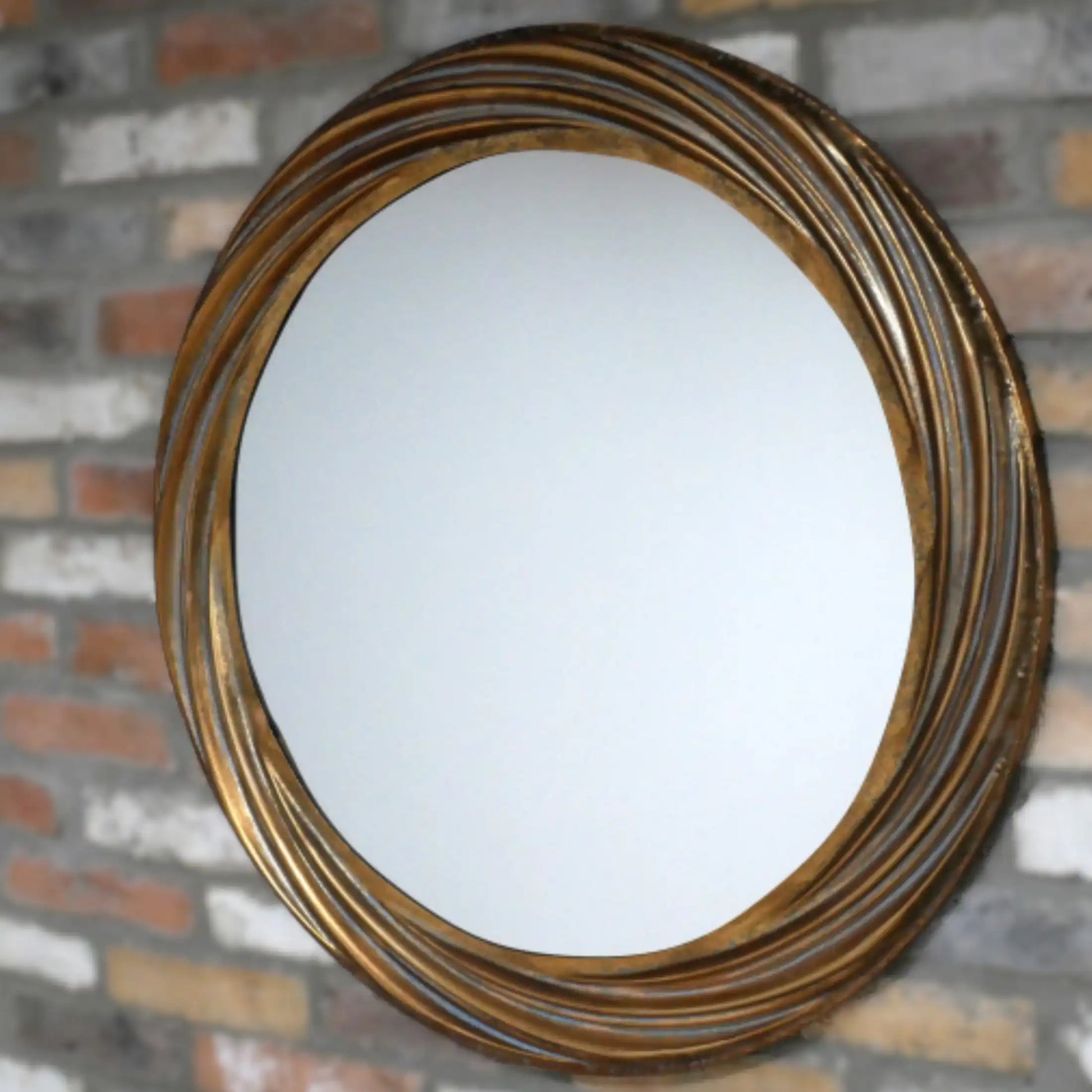 Round mirror with a gold frame on a brick wall