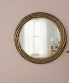 Round decorative mirror with a gold frame on a pink wall