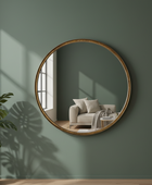 Round wooden-framed mirror on a green wall reflecting a cozy living room.