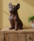 Decorative statue of a dog on a wooden surface with a plant in the background
