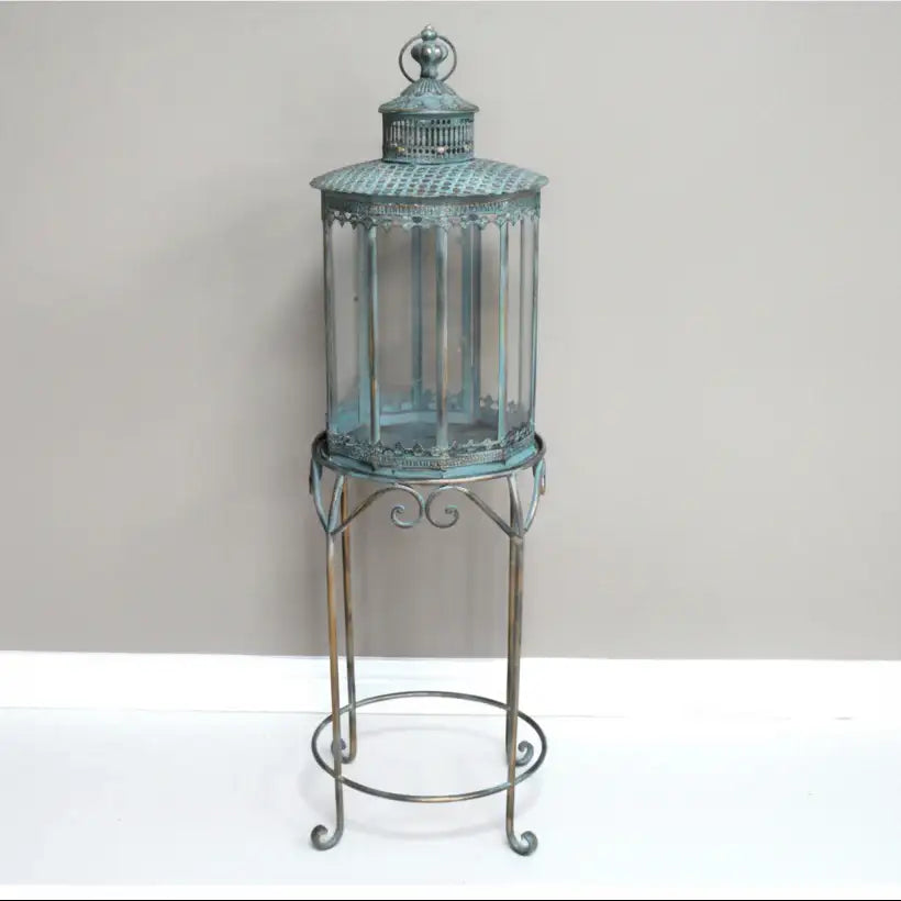 Decorative lantern with glass panels on a metal stand against a plain background