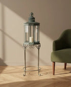 Decorative lantern on a stand next to a green armchair in a room with wooden flooring and beige walls.