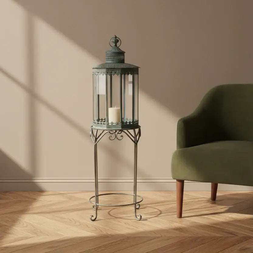 Decorative lantern on a stand next to a green armchair in a room with wooden flooring and beige walls.