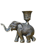 Decorative brass elephant candle holder on a wooden surface with a gray background