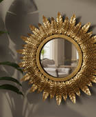 Decorative gold mirror with leaf-like patterns on a wall.