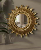 Decorative gold mirror with leaf-like patterns on a wall.