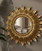 Decorative gold mirror with leaf-like design on a wall