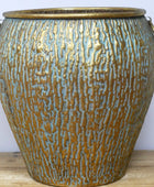 Decorative vase with textured surface and gold accents on a wooden surface.