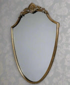 Decorative gold-framed mirror on a floral wallpapered wall