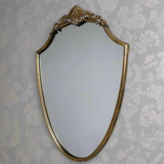 Decorative gold-framed mirror on a floral wallpapered wall