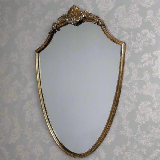 Decorative gold-framed mirror on a floral wallpapered wall