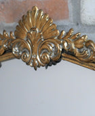 Decorative gold mirror with intricate designs on a white background