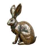 Bronze rabbit sculpture on a wooden surface with a gray background