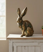 Bronze rabbit sculpture on a wooden surface with a neutral background