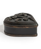 A small heart-shaped black wooden keepsake box with an ornate carved lid, photographed on a clean white background.